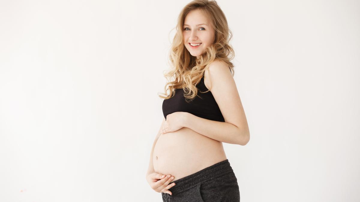 close-up-portrait-happy-handsome-young-mother-with-blonde-wavy-hair-black-sport-clothes-holding-stomach-with-hands-looking-camera-with-relaxed-expression_71641600
