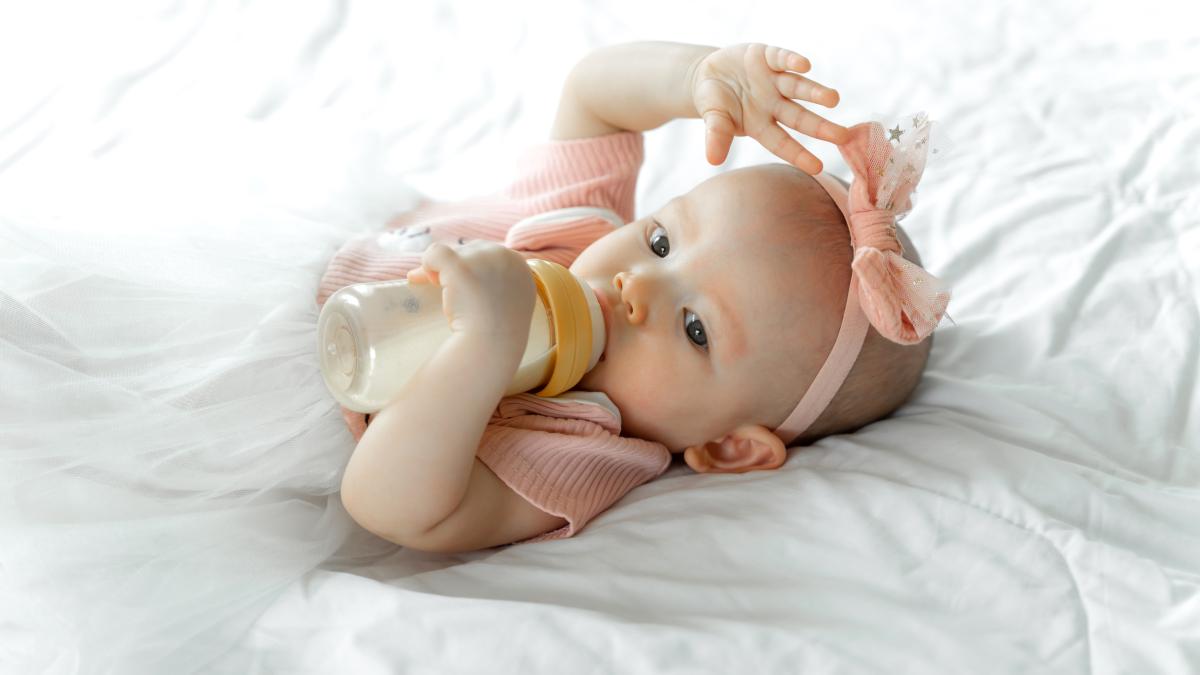 baby-drinks-milk-from-bottle-white-bed_40171600