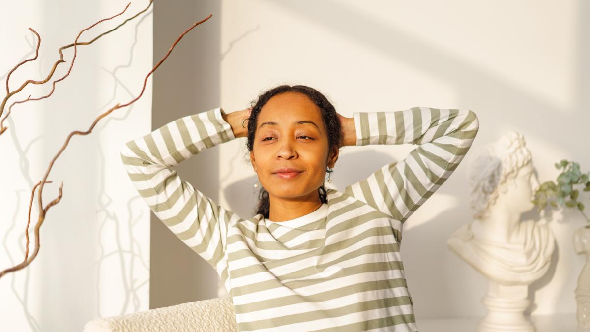 smiling-african-american-female-looking-window-natural-light-from-sunset-enjoying-moment_59209600