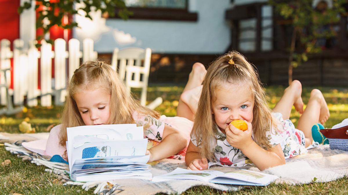 cute-little-blond-girls-reading-book-outside-grass_04386200
