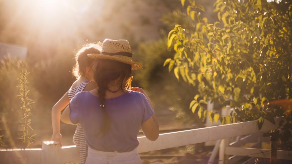 rear-view-mother-carrying-her-daughter-near-fence_94868700