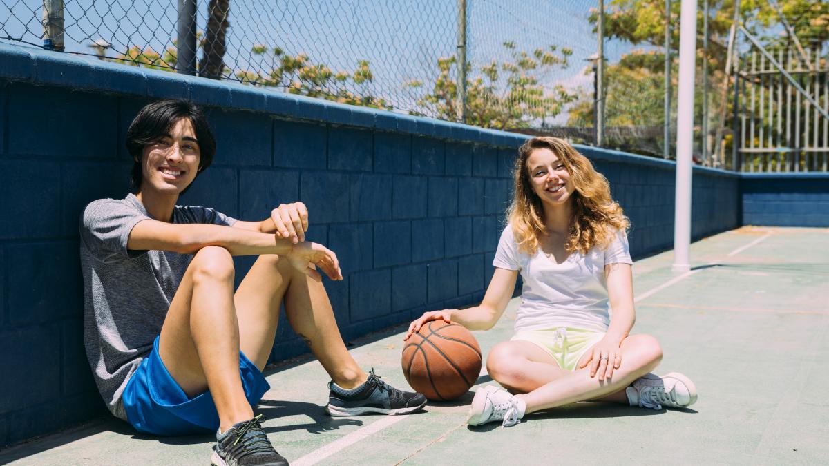 happy-teenagers-sitting-basketball-pitch_71138900