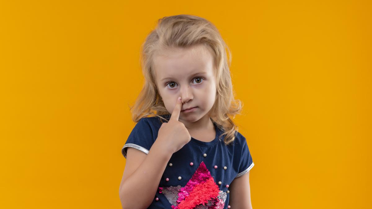 beautiful-little-girl-with-blonde-hair-wearing-navy-blue-shirt-pointing-her-face-with-index-finger-orange-wall_87216400