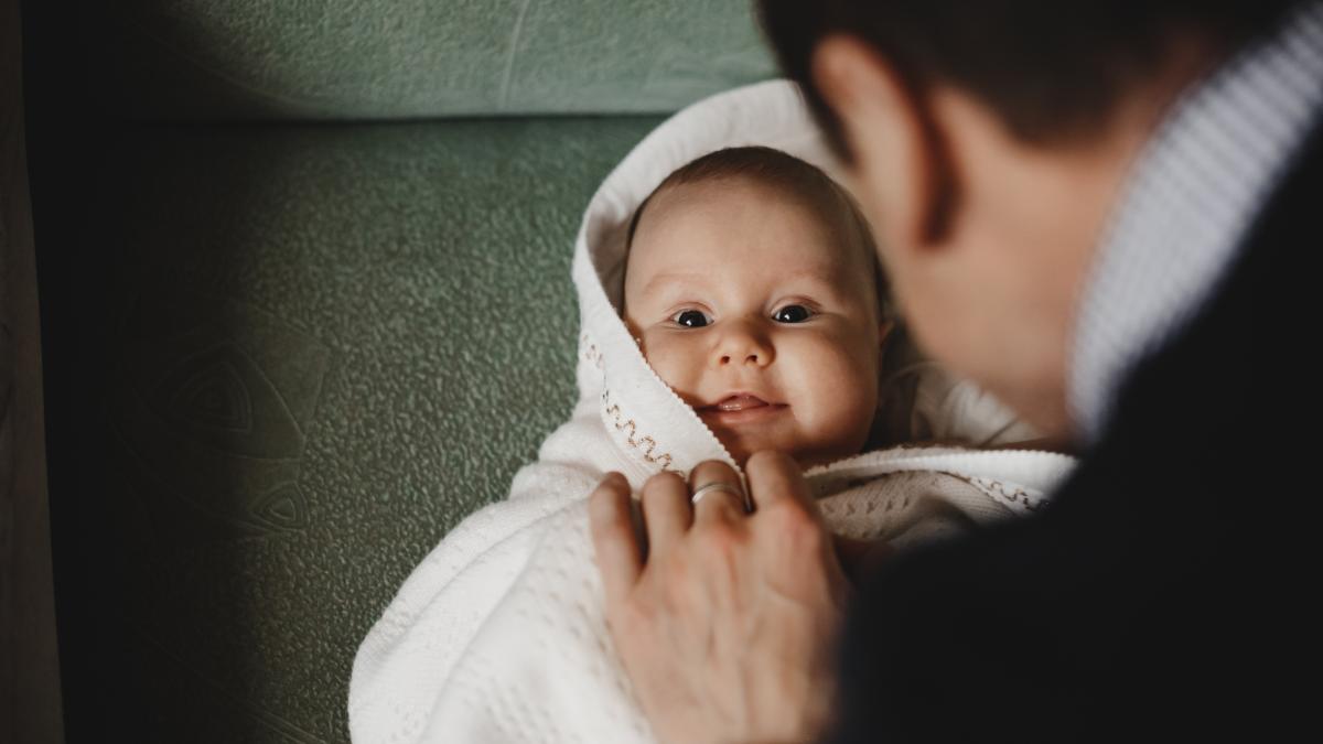 man-plays-with-little-newborn-baby-enveloped-soft-blanket_71418800