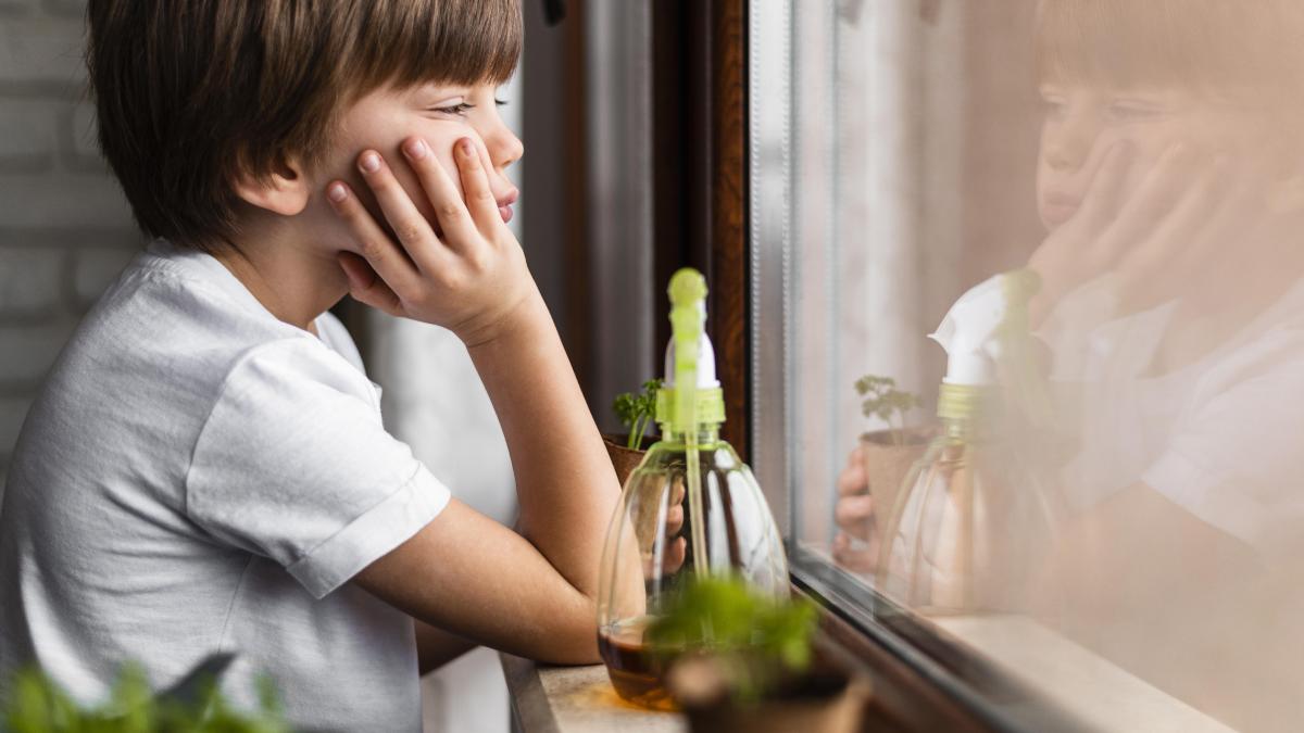 side-view-little-boy-looking-through-window-with-water-spray-crops_02337500
