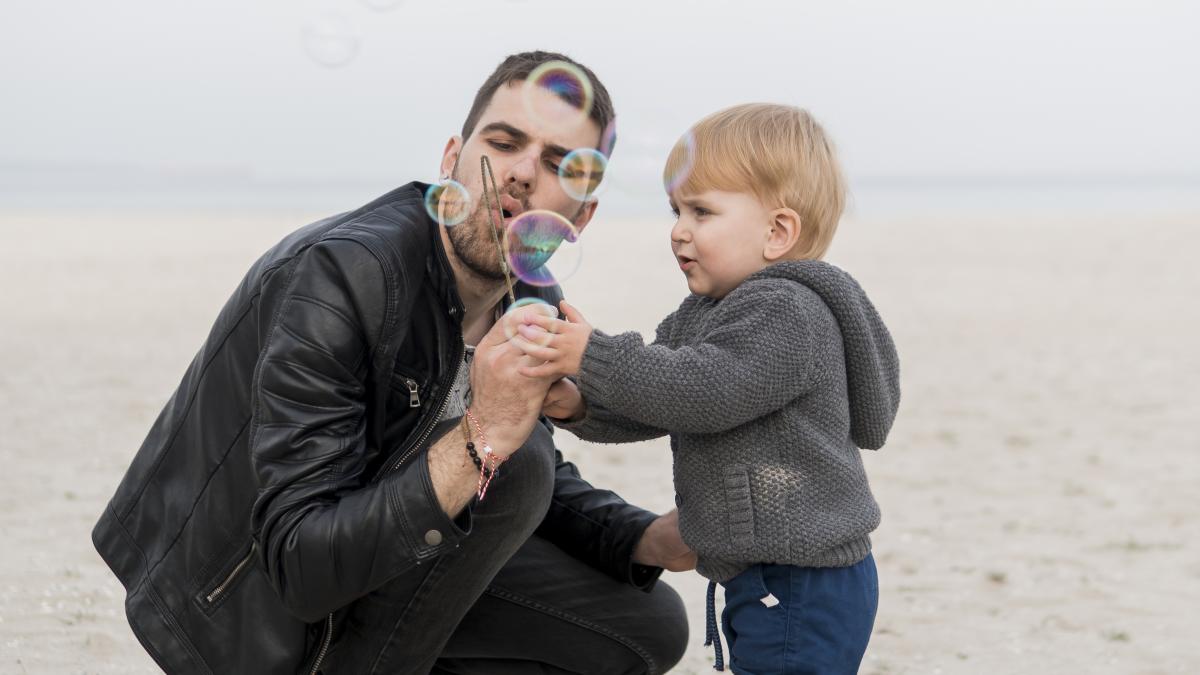 father-son-making-soap-bubbles-beach_97598500
