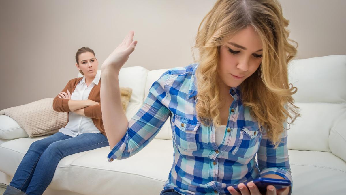 daughter-gesturing-while-using-mobile-phone-sofa-home_33257700