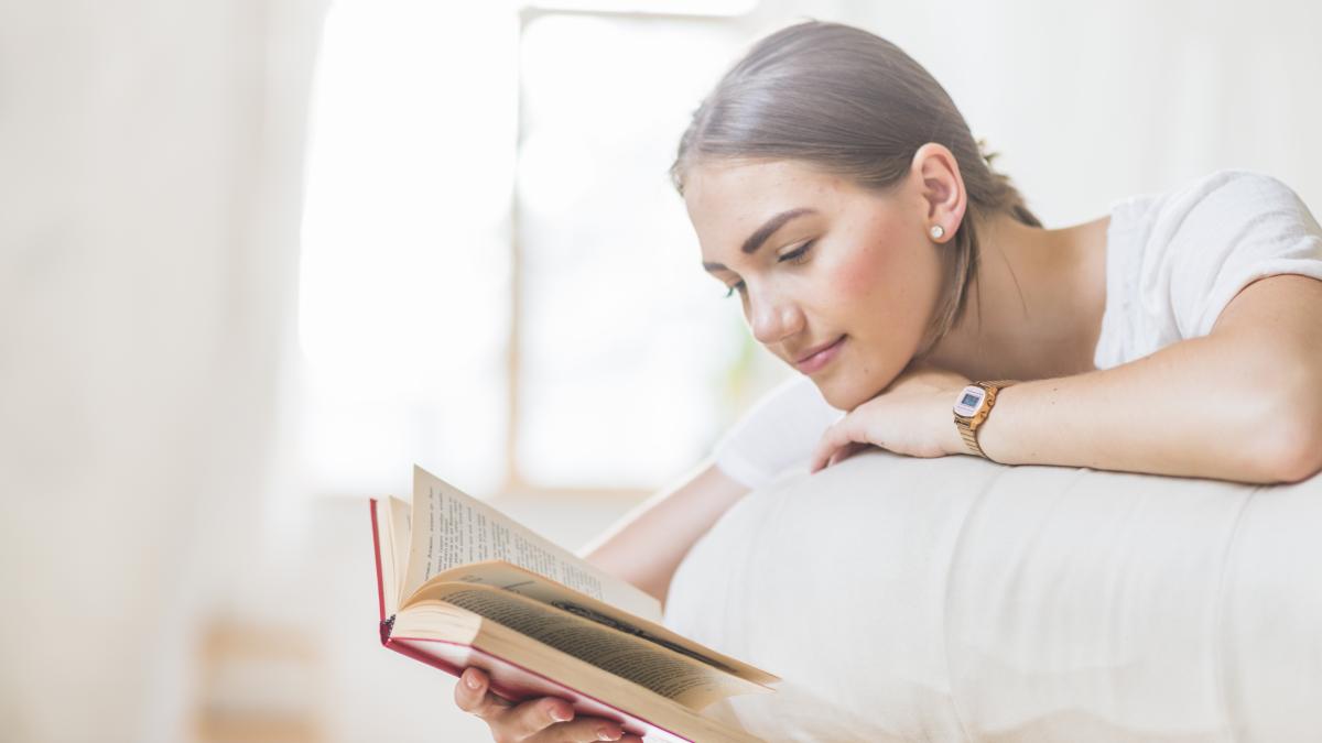 woman-lying-bed-reading-book-home_55701000