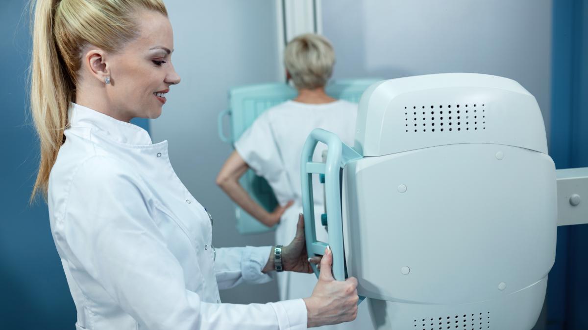 mid-adult-smiling-nurse-taking-xray-patient-clinic_80847800