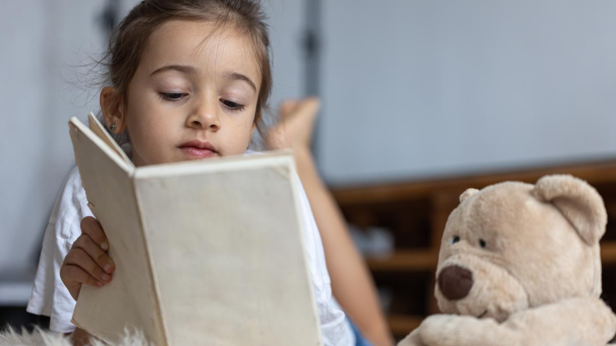 cute-little-girl-home-lying-floor-with-her-favorite-toy-reads-book_64158700