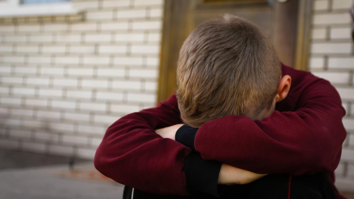 copil-trist-sta-cu-capul-pe-genunchi