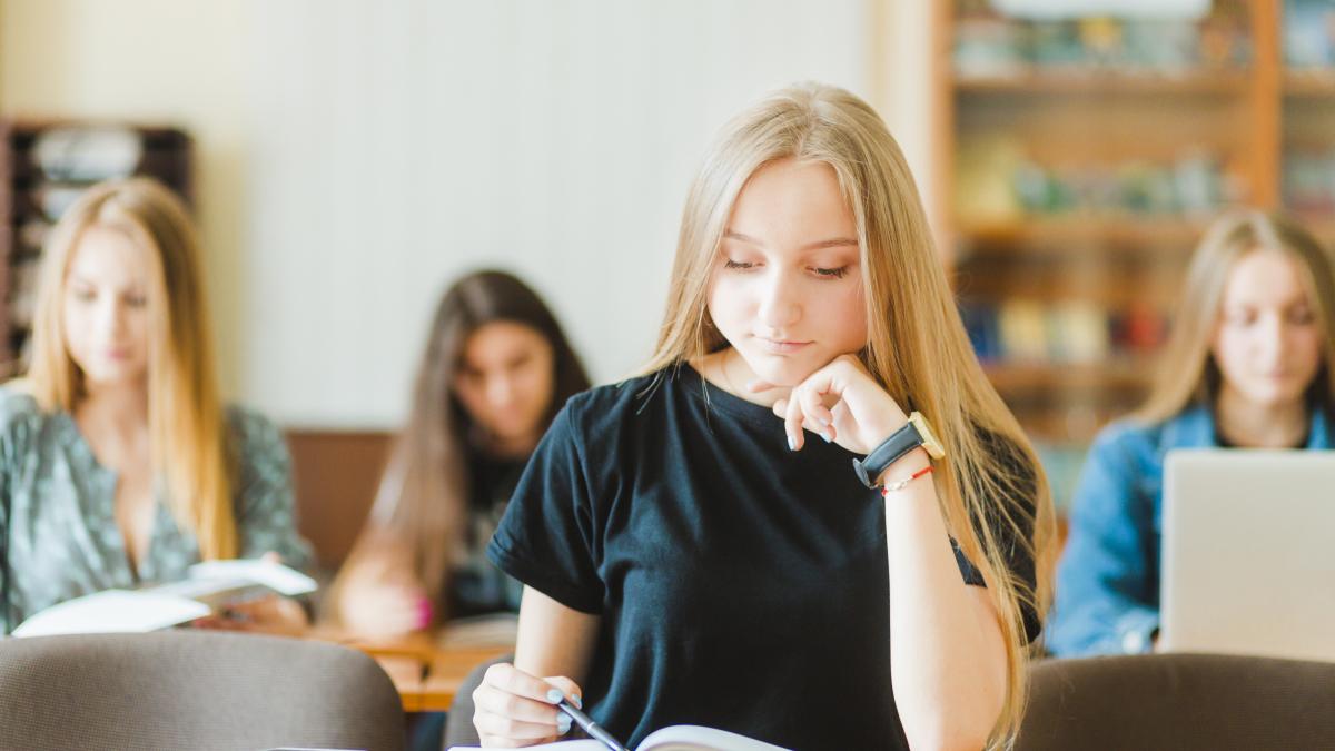 Elevă stând în bancă învățând