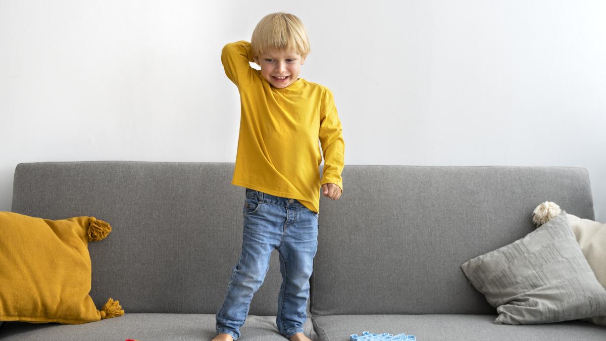 copil stând pe canapea râzând