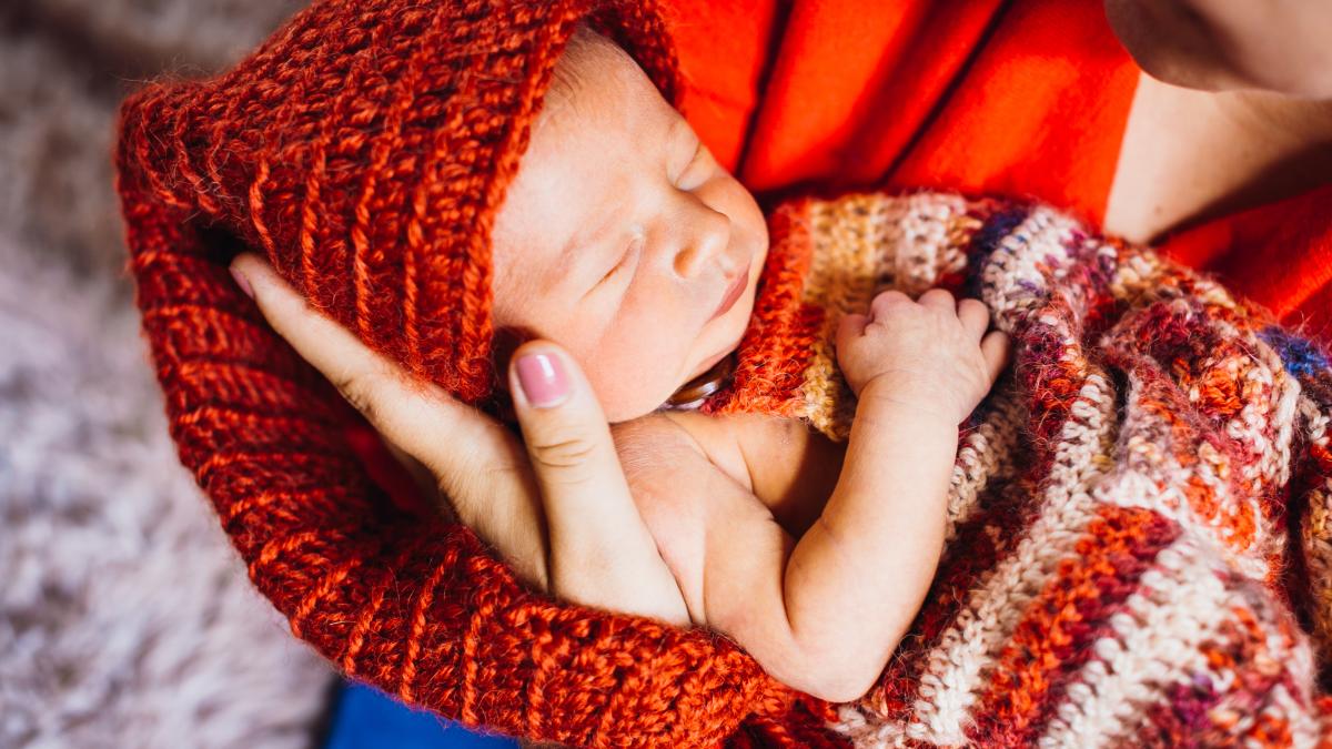 bebeluș care stă în brațe și doarme