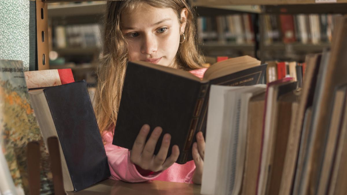fată citind la bibliotecă