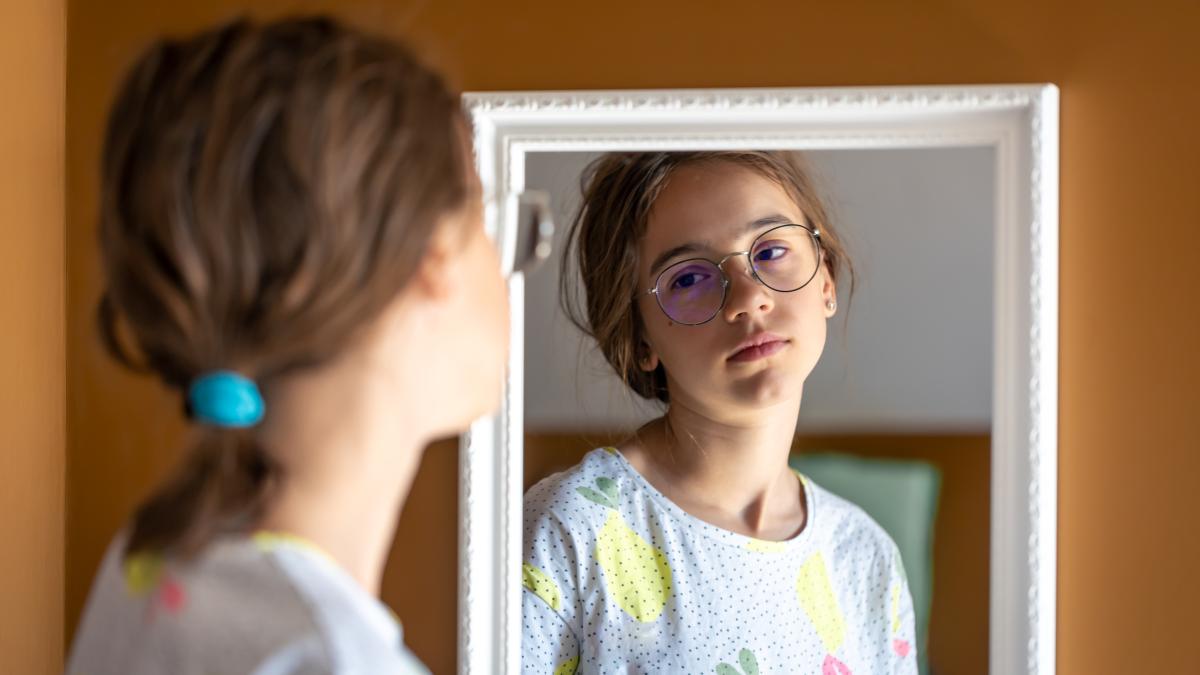 adolescentă tristă uitându-se în oglindă
