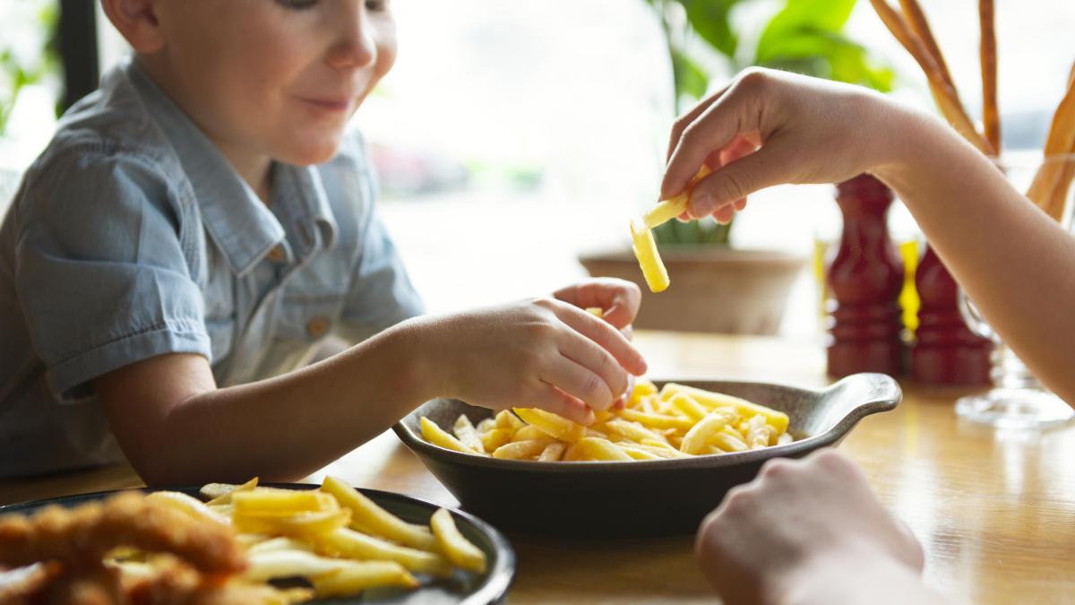 copil care mănâncă cartofi prăjiți