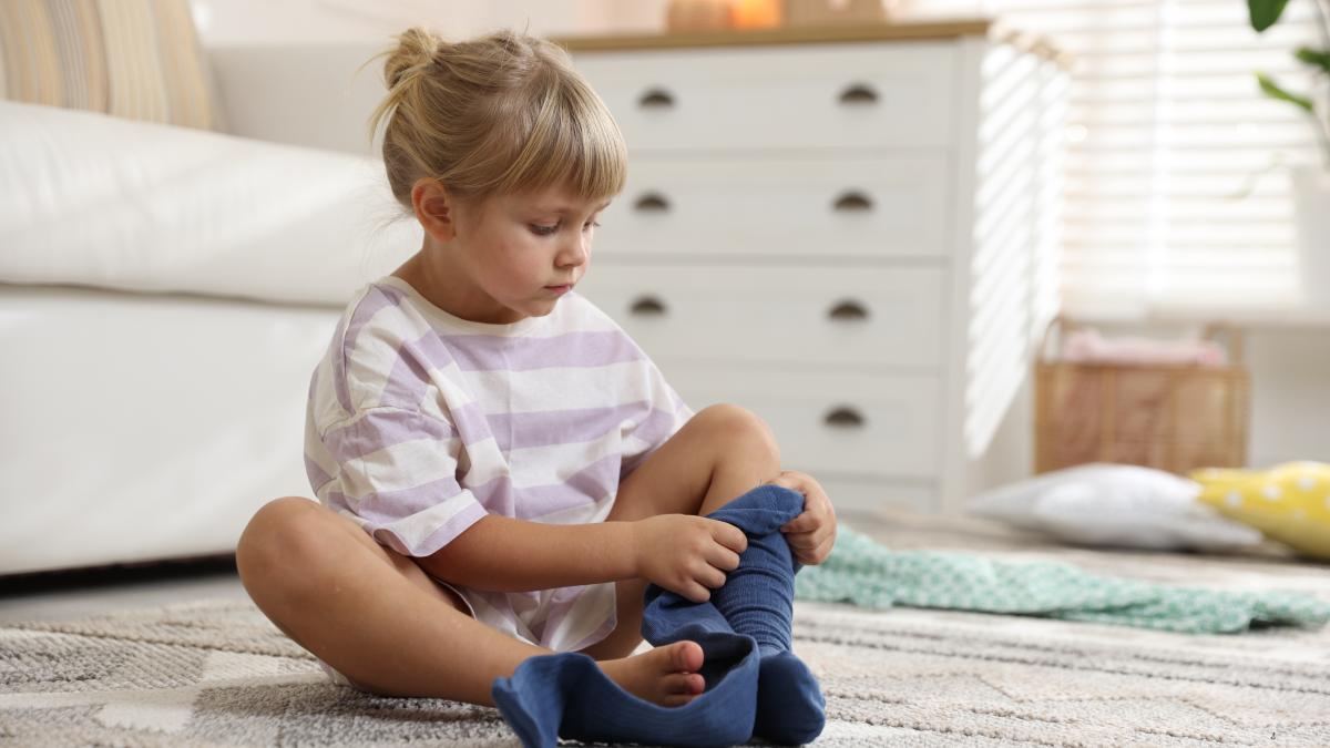 copil care își pune șosetele